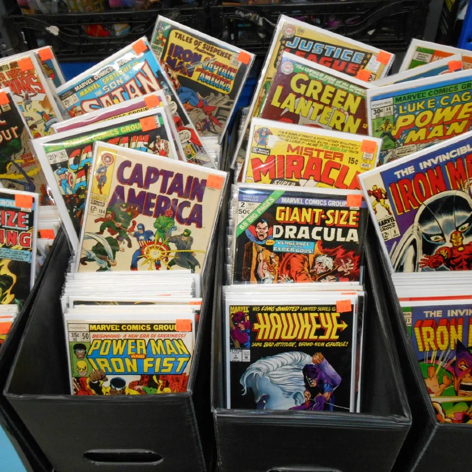 Short boxes of bagged comics faced up — Captain America, Justice League, Power Man and Iron Fist